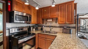 A kitchen with wooden cabinets, stainless steel appliances, granite countertops, and a visible fire extinguisher.