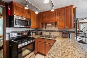 A kitchen with wooden cabinets, stainless steel appliances, granite countertops, and a visible fire extinguisher. - Hutch 1- 2 Min Walk to Slopes, Great Mountain View (Slaty Fork)