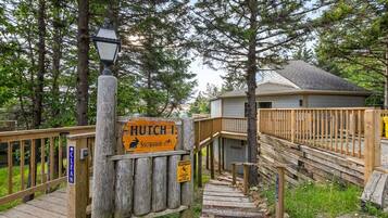 A wooden staircase leading to a cabin labeled 'Hutch 1 Snowshoe' with a caution sign for slippery steps.
