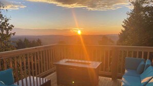 A deck with a table and blue seating, overlooking a sunset. - Hutch 1- 2 Min Walk to Slopes, Great Mountain View (Slaty Fork)