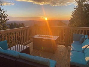 A deck with a table and blue seating, overlooking a sunset. - Hutch 1- 2 Min Walk to Slopes, Great Mountain View (Slaty Fork)
