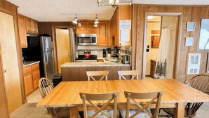 A kitchen with wooden cabinets, a stainless steel refrigerator, a microwave, and a stove. There is a wooden dining table with four chairs. - Hutch 1- 2 Min Walk to Slopes, Great Mountain View (Slaty Fork)
