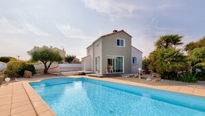 Una piscina con una casa al fondo.