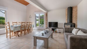 A spacious living area with a dining table, chairs, a sofa, a TV, and a fireplace. - 200m from the sea, 6 adults and 4 children (La Plaine-sur-Mer)
