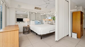 A modern bedroom with a large bed, a ceiling fan, a TV, and a wooden desk. - Ocean View Luxury Rental at Waikiki Shore #303! Steps to Beach! (Honolulu)