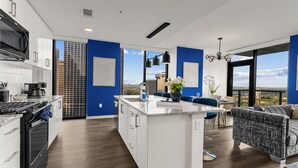 A modern kitchen with white cabinets, a black microwave, and a large island with a vase of flowers.