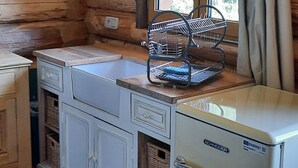 Una cocina compacta con paredes de madera, un refrigerador integrado y una ventana con cortinas.