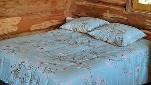 Una habitación de cabaña de madera con cama, paredes de madera y una ventana.