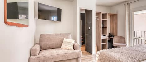 Un dormitorio pequeño con sofá, cama, armario y espejo.