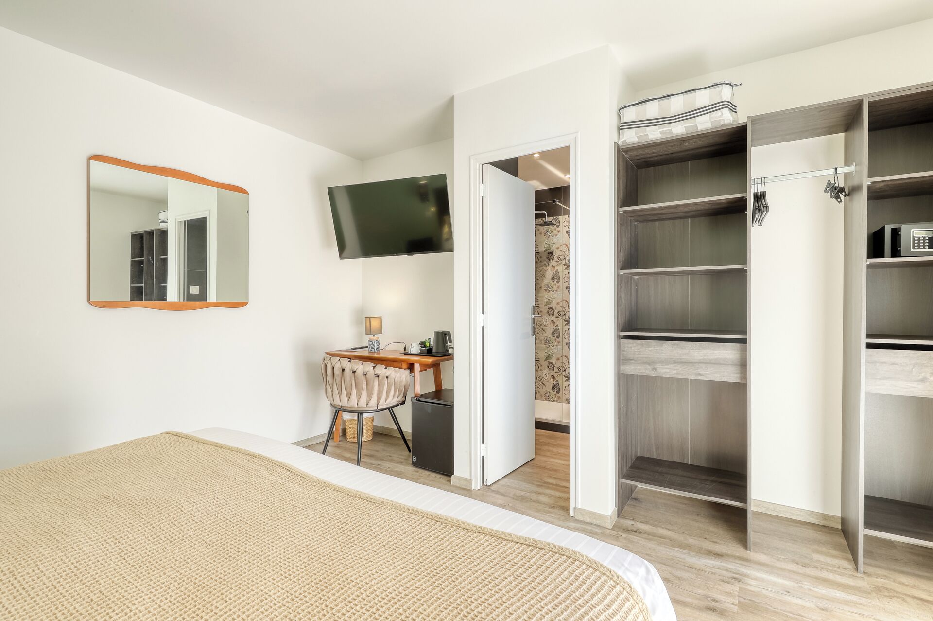 Un dormitorio con cama, escritorio, silla, televisión y vestidor.