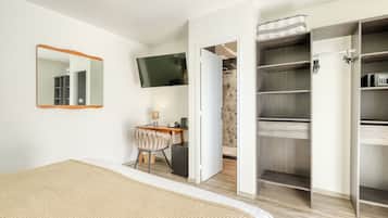A bedroom with a bed, a desk, a chair, a TV, and a walk-in closet.