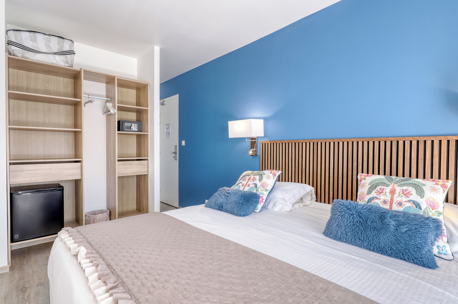 Un dormitorio con una cama, un armario, una lámpara de noche y un pequeño electrodoméstico negro.