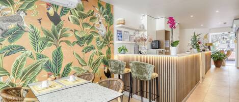 A restaurant with a tropical-themed wall, a bar area, and a reception desk.