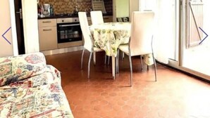 A compact living space with a dining area, kitchenette, and a patterned sofa.