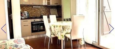 A compact living space with a dining area, kitchenette, and a patterned sofa.