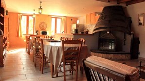 A cozy dining area with a long table, chairs, and a fireplace.