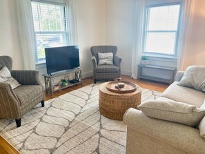 Un salon équipé d’un téléviseur à écran plat, de deux fauteuils, d’un canapé, d’une table basse ronde et d’un tapis à motifs.