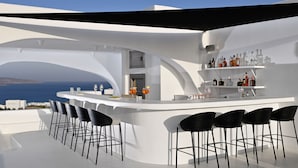 A modern bar area with a curved white countertop, black bar stools, and a view of the sea. - Million Stars Mykonos (Mykonos)