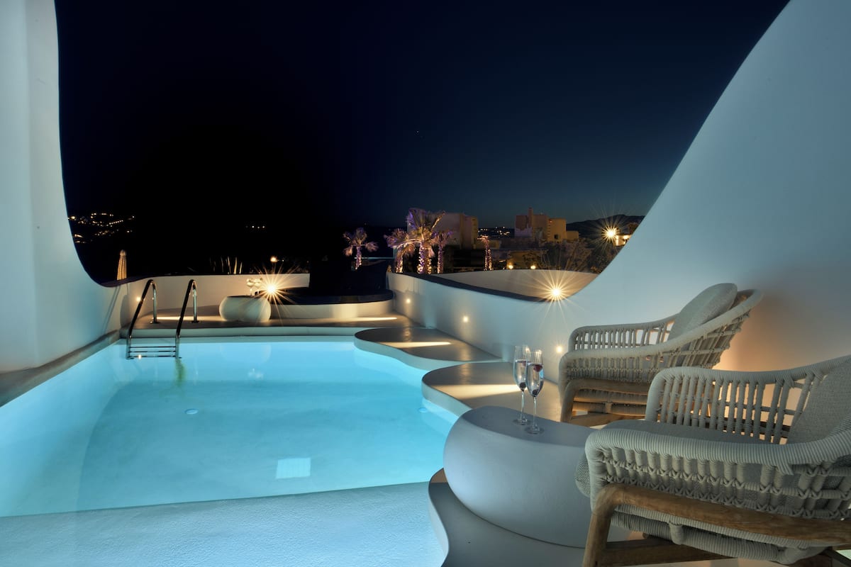 A modern rooftop pool area with a clear view of the cityscape at night.