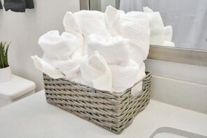 A wicker basket filled with white towels on a bathroom counter. - Downtown Houston Luxury Mid-Rise Apartment (Houston)