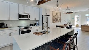 A modern kitchen with white cabinetry, a large island, and pendant lighting. - Gulf Place Spires #7B | Luxe Townhome, Near Beach (Santa Rosa Beach)