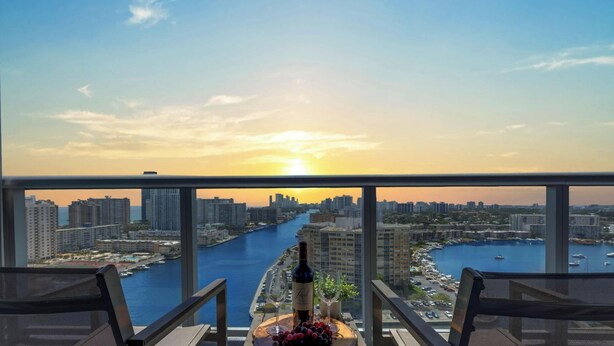 A balcony with a city view, a bottle of wine, and a fruit platter. - Amazing View Balcony - 1BR- Pool & Gym (Hallandale Beach)