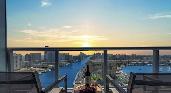 A balcony with a city view, a bottle of wine, and a fruit platter.
