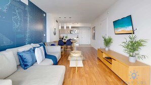 A modern living room with a sofa, a coffee table, a TV, and a wall with a map. - Amazing View Balcony - 1BR- Pool & Gym (Hallandale Beach)