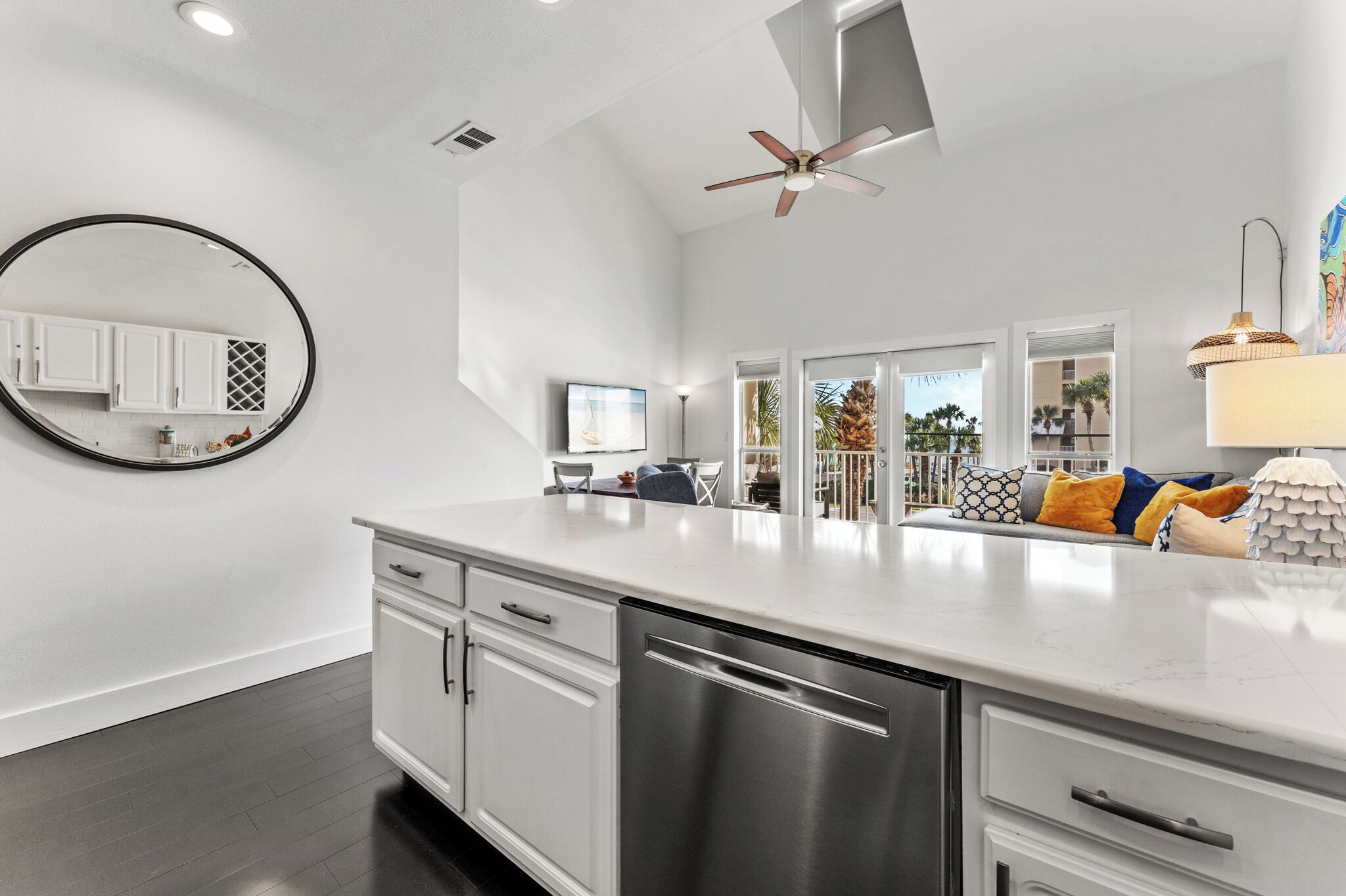 A modern kitchen with a large island, white cabinetry, and a dishwasher.