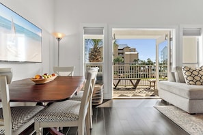 Relax in this stylish living room with a dining table for two, a large flat-screen TV, and a balcony with a residential view.