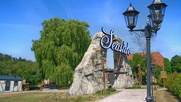 A pathway leading to a sign that reads "Seaside" with a large rock formation and a street lamp.