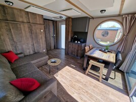 Una sala moderna con un sofá, una mesita redonda y un comedor con una mesa de madera y sillas.