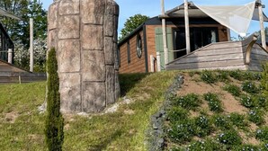 A metal sculpture of a horse on a stone pedestal in a landscaped area with a building in the background. - Seaside-Resort (Geiselwind)