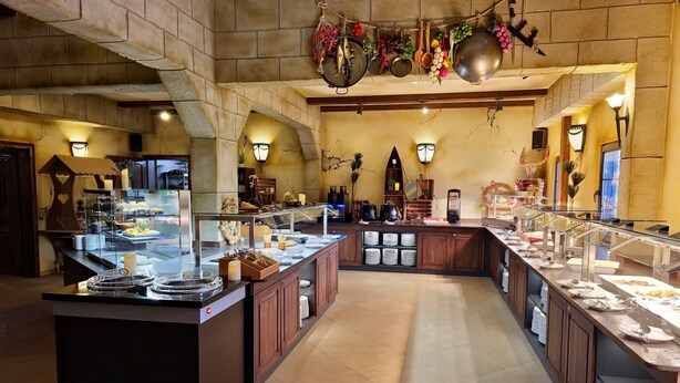 A spacious buffet area with multiple serving stations, a central island, and a variety of food items displayed. - Seaside-Resort (Geiselwind)