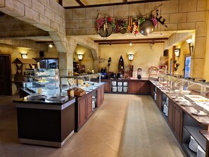 Un vaste espace buffet doté de plusieurs points de service, d’un îlot central et d’une grande variété de plats présentés.