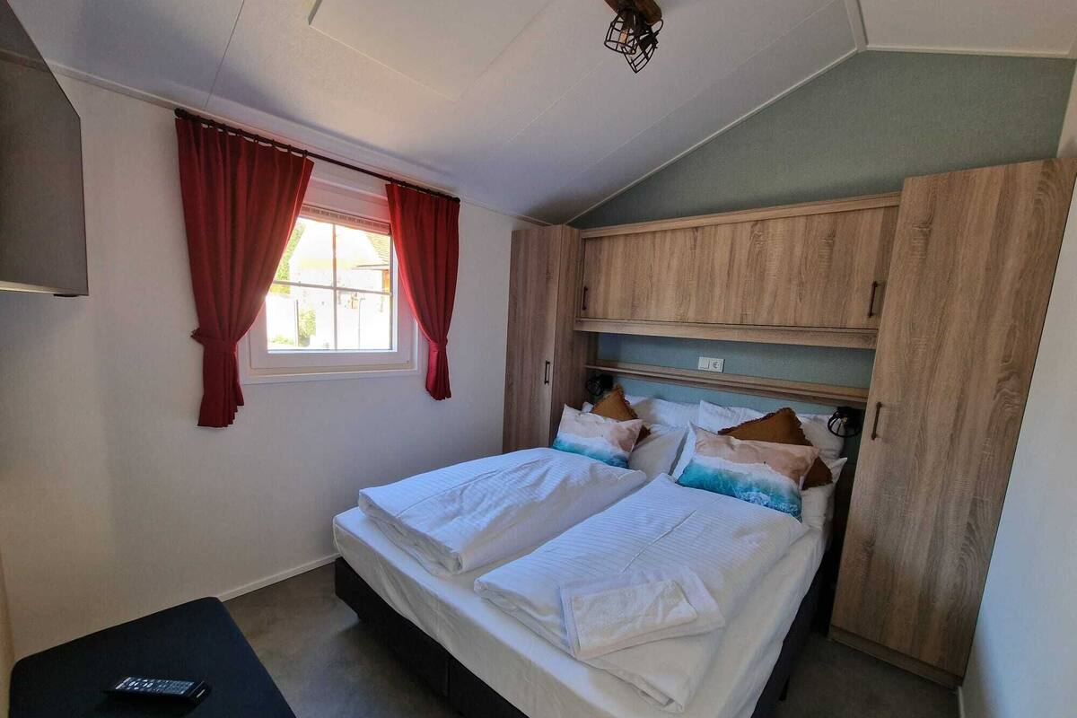 A bedroom with a bed, a desk, and a wardrobe.
