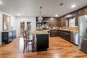A modern kitchen with dark wood cabinets, stainless steel appliances, and a central island.
