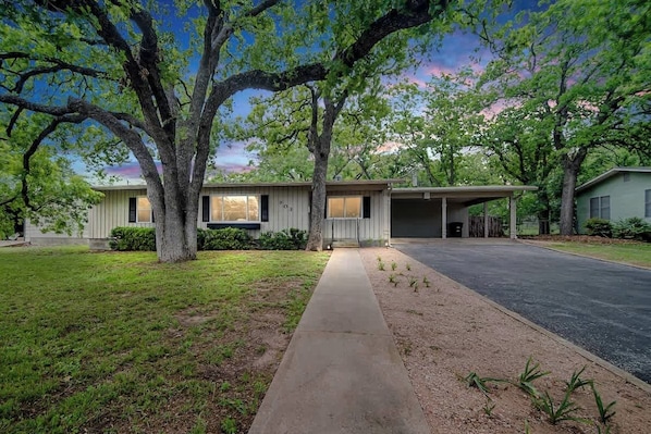 A single-story house with a garage, a covered driveway, and a well-maintained lawn.