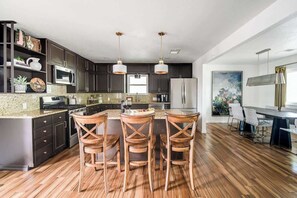 Una cocina moderna con armarios oscuros, piso de madera e isla central con taburetes de bar.