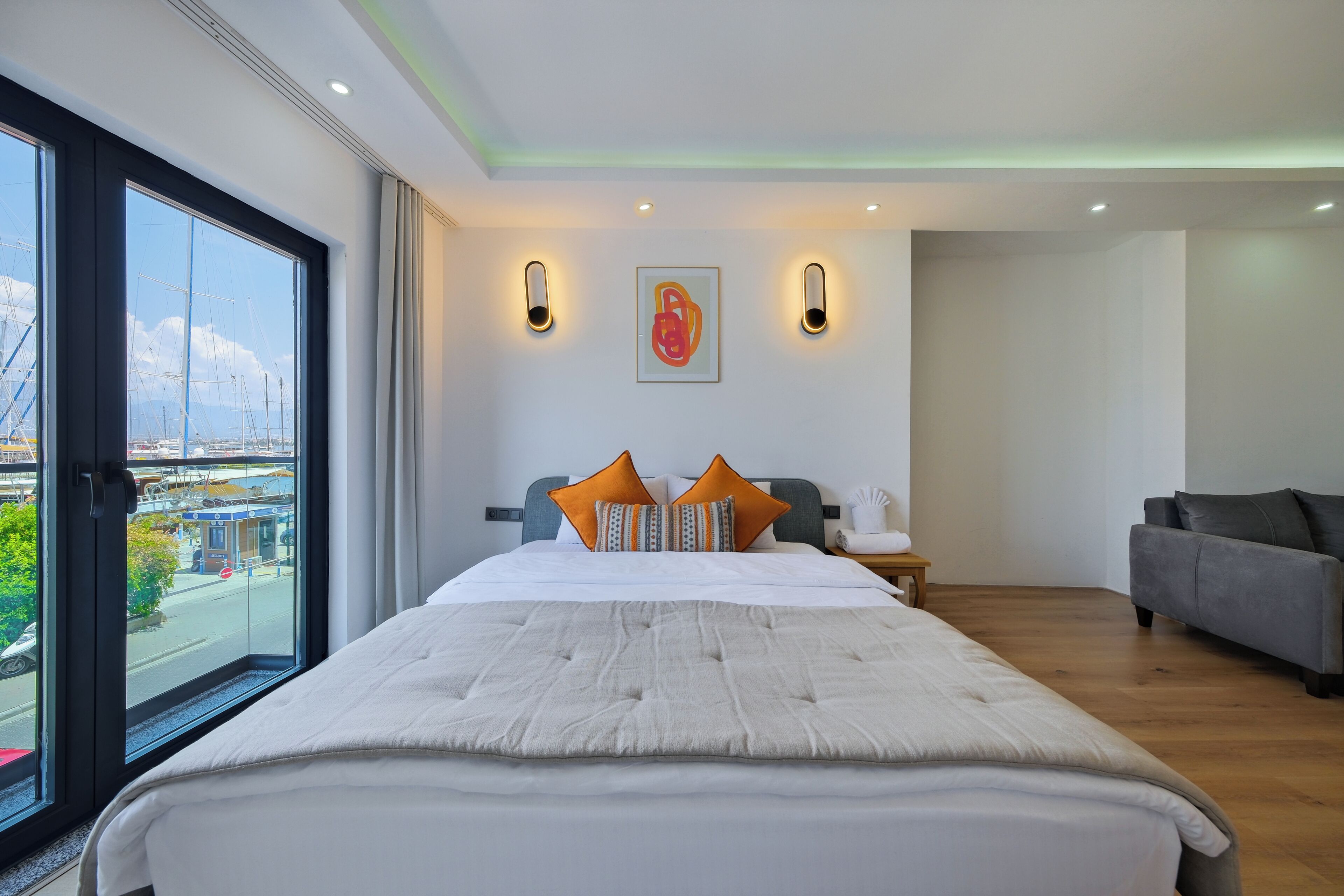 Habitación de hotel con una cama grande, un sofá, vistas de la ciudad y un cuadro en la pared.