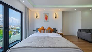Habitación de hotel con una cama grande, un sofá, vistas de la ciudad y un cuadro en la pared.