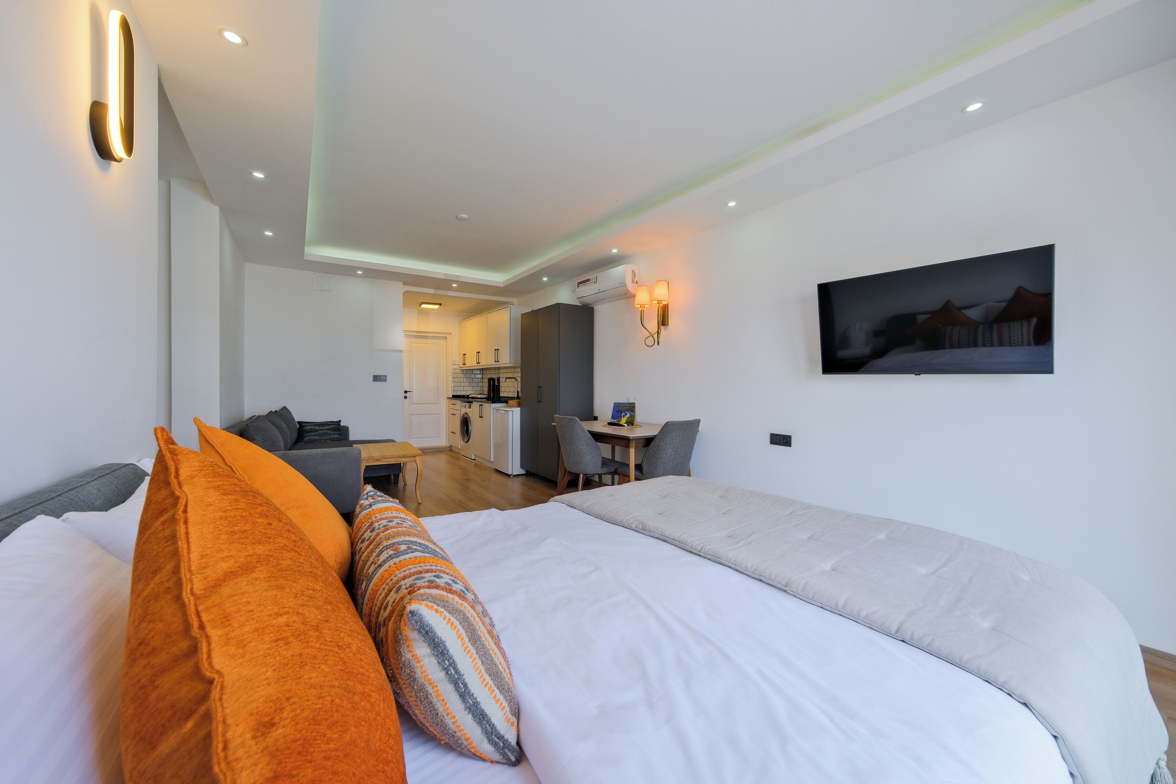 A hotel room with a bed, a desk, and a kitchenette.