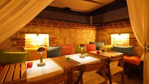 A cozy room with a brick wall, a wooden table, and a cushioned bench. - Portakal Cicegi Alaçatı  (Cesme)