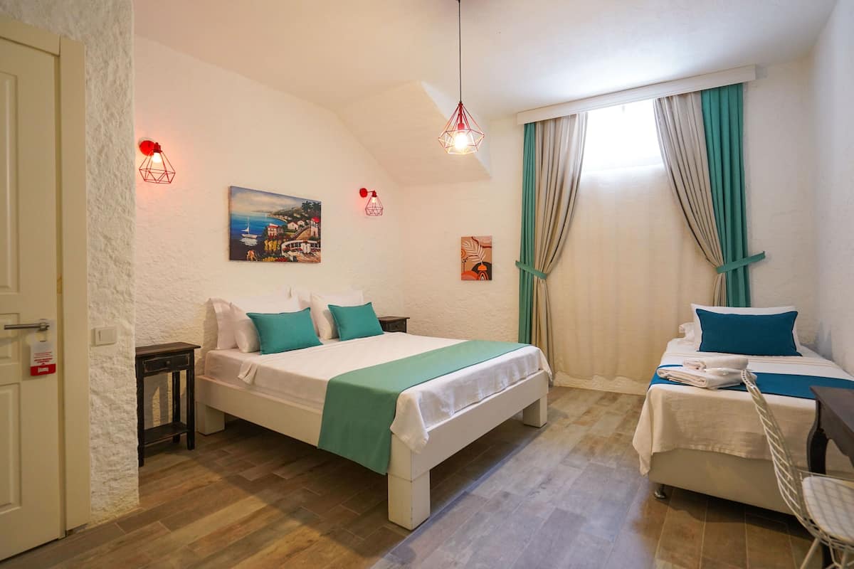 A hotel room with two beds, a painting on the wall, and a window with curtains.