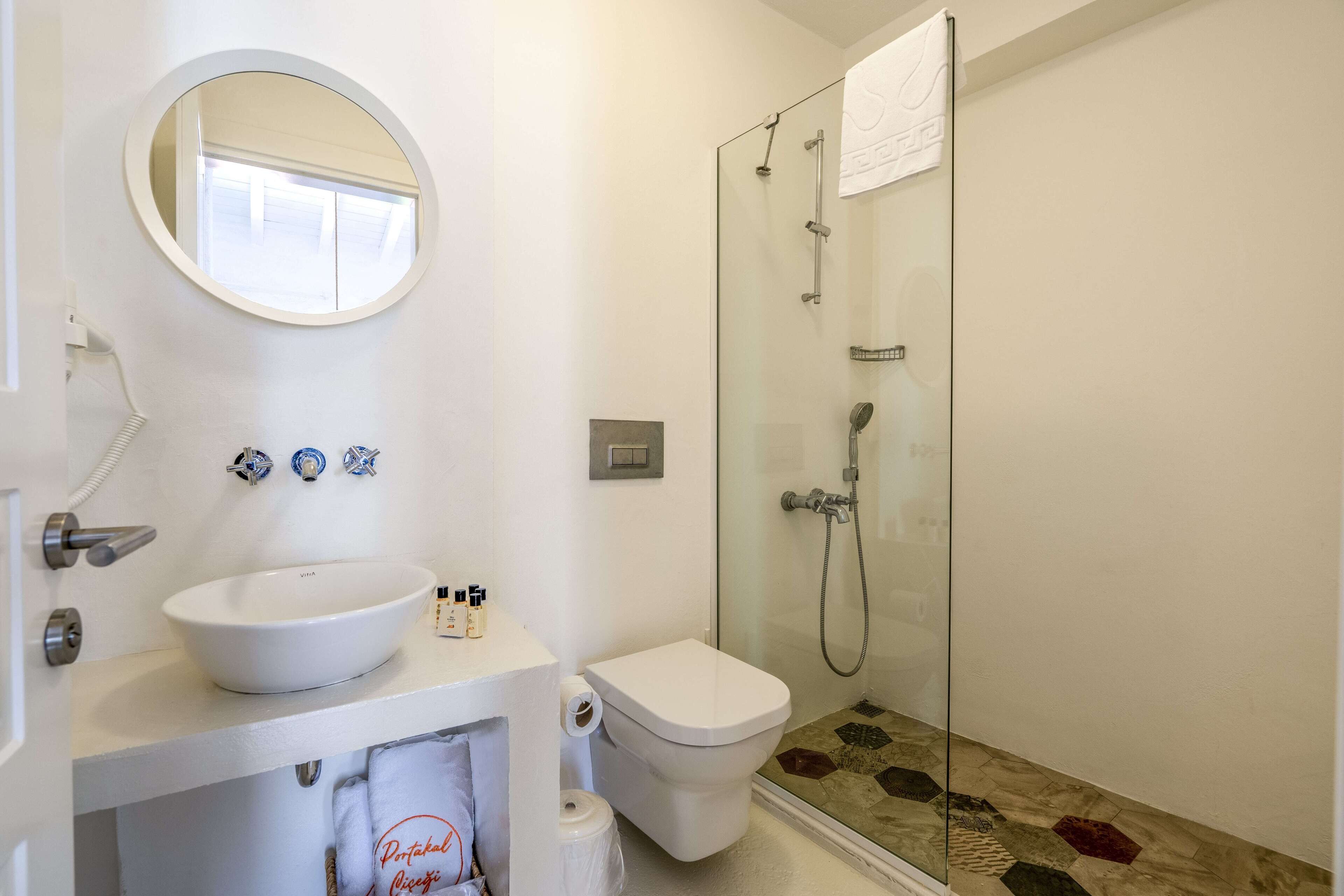 Un baño con lavamanos blanco, inodoro y ducha con mampara de vidrio.