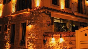 A stone building with multiple windows and balconies, illuminated by warm lighting. - Portakal Cicegi Alaçatı  (Cesme)
