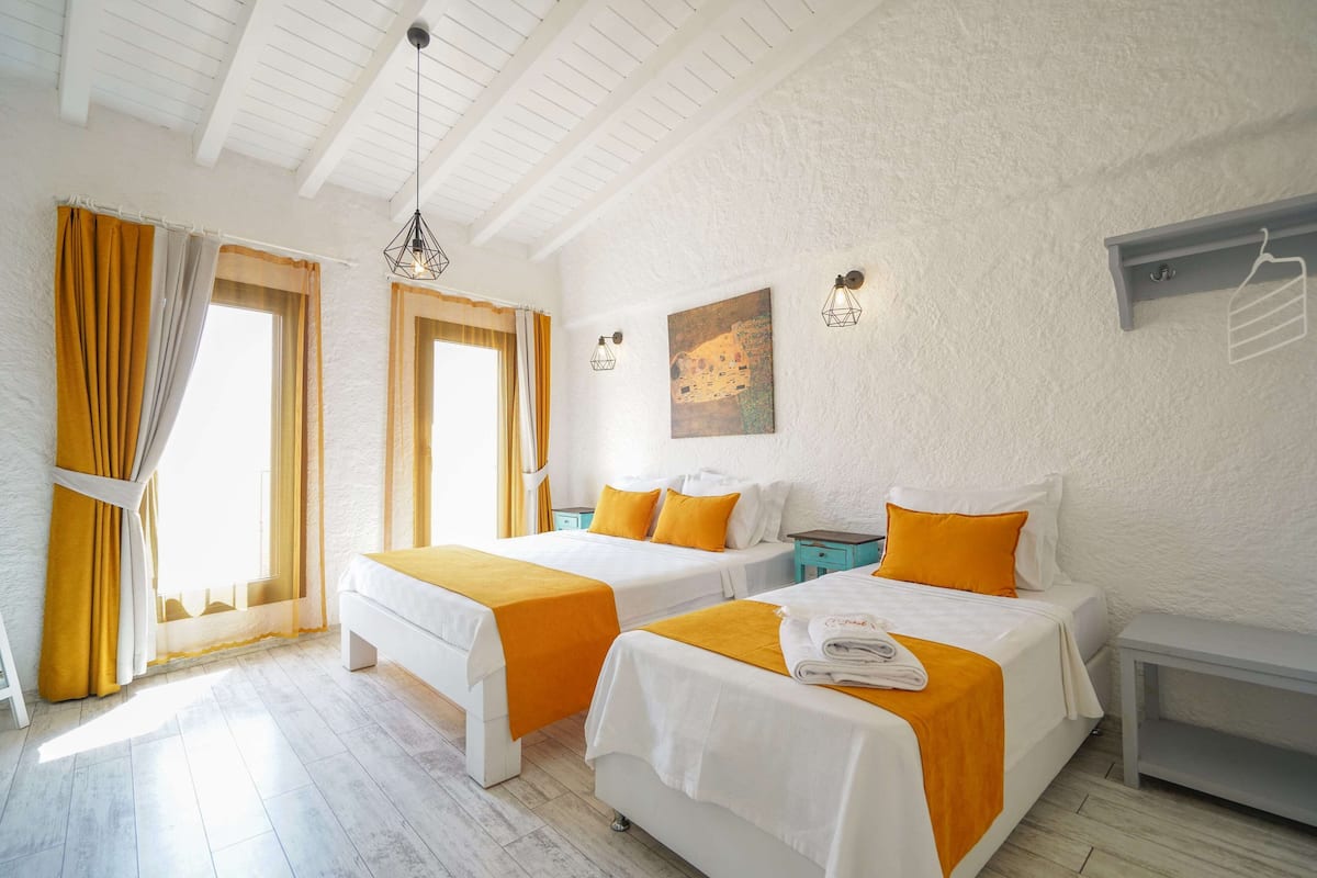 A hotel room with two beds, a painting on the wall, and a hanging rack.