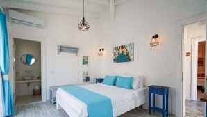 A bedroom with a bed, bedside tables, a wall-mounted air conditioner, a hanging light fixture, and a painting. - Portakal Cicegi Alaçatı  (Cesme)