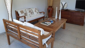 Un salon avec un canapé en bois, une table à manger en bois, un téléviseur et un meuble en bois.
