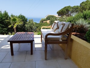 A patio with a wooden table and a cushioned bench, overlooking a scenic view of the sea and greenery. - Appart , Belles Prestations Avec Terrasse vue mer Dans Villa (.CALCATOGGIO)